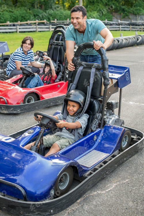 Preview: Boys and men go-karting on a track.
