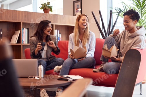 Preview: Group Of Young Businesswomen Sitting On Sofas In Open Plan Workspace Having Working Lunch Meeting
