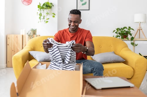 Preview: Happy african man opening cardboard box at home