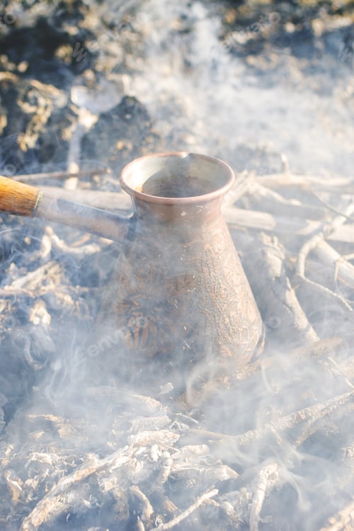 Preview: Boiling coffee in turkish cezva on campfire coals.
