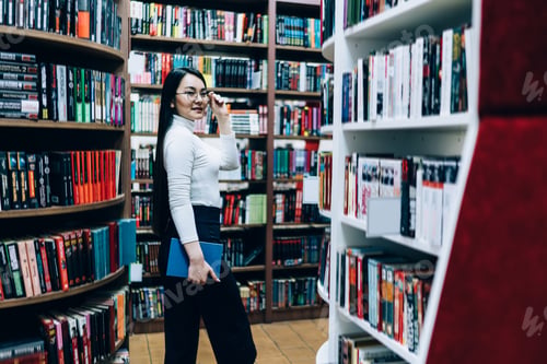 Preview: Young female looking for books in library