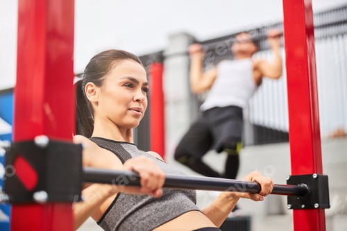 Preview: Motivated young couple training together on sports ground