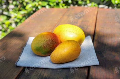 Preview: Many tasty mango fruits on wooden table outdoors