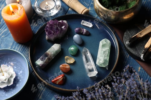 Preview: Chakra gemstones, lavender flowers, incense and burning candles on blue wooden table, closeup