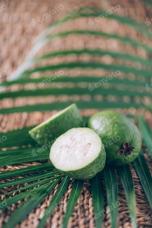 Preview: Tropical fruit feijoa over palm leaves on rattan background. Copy space. Acca sellowiana. Creative