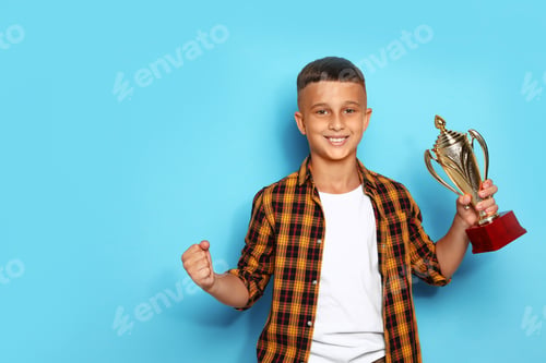 Preview: Happy boy with golden winning cup on blue background