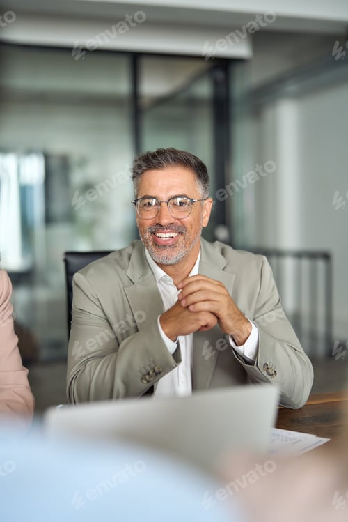 Preview: Smiling Latin business man manager working at team office meeting table.