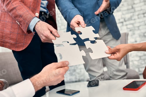 Preview: Cropped image of businesspeople joining puzzle pieces in office