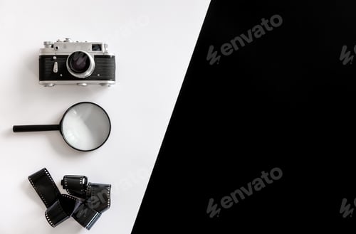 Preview: Vintage retro camera, magnifier and film on black and white background.
