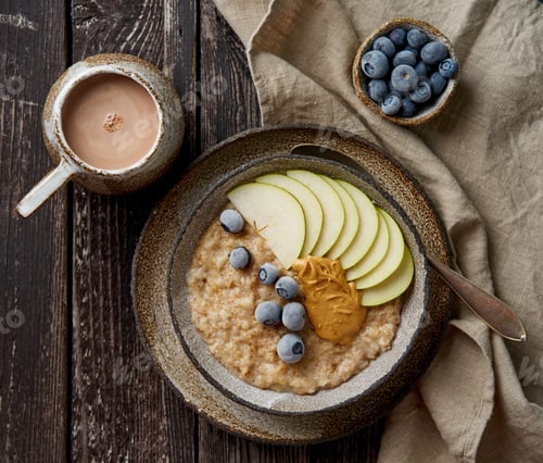 Preview: Oatmeal, healthy porridge in large bowl with fruits and berry for breakfast, cup of cocoa.