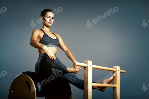 Preview: Beautiful woman doing pilates exercise, training on barrels. Barrel reformer, correct posture