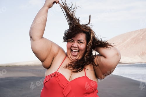 Preview: Curvy overweight woman smiling with beach on background - Focus on face