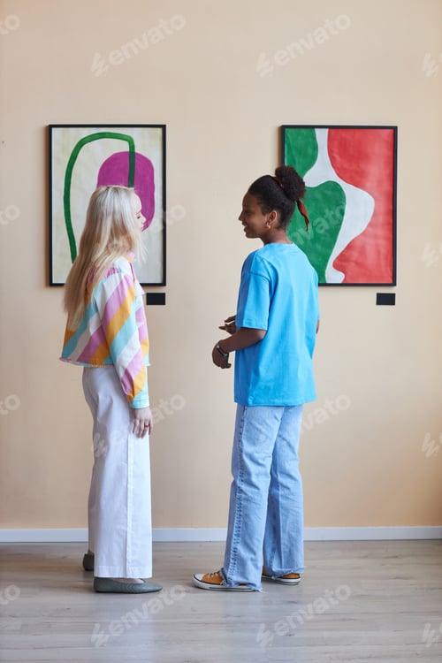 Preview: Two teen girls discussing pictures in art gallery