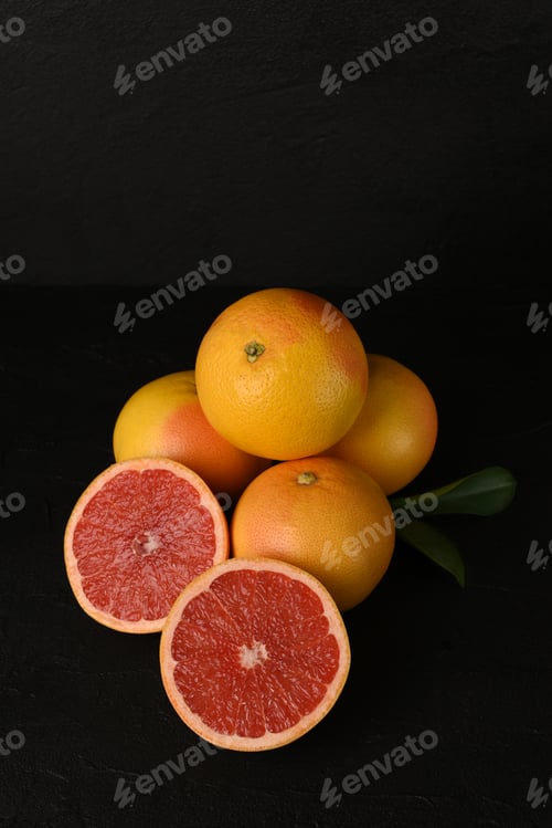 Preview: Few fresh juicy grapefruits on dark background. Ripe fruits with leaves. Copy space.