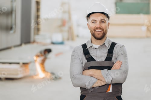 Preview: Construction worker smiling with crossed arms in modular building industry