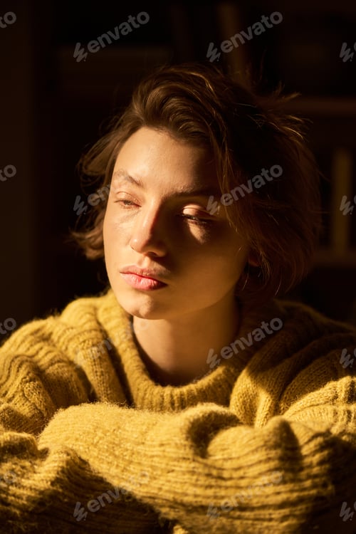 Preview: Portrait of Young Woman Sitting Indoors Reflecting in Sunlight
