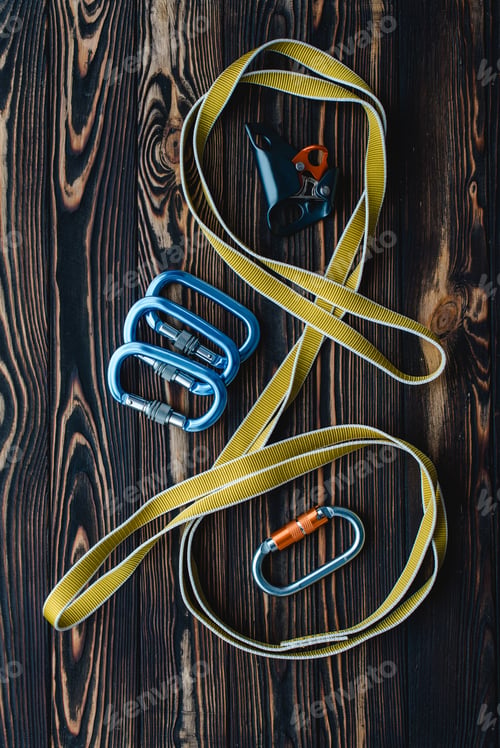 Preview: Isolated photo of climbing equipment. Parts of carabiners lying on the wooden table