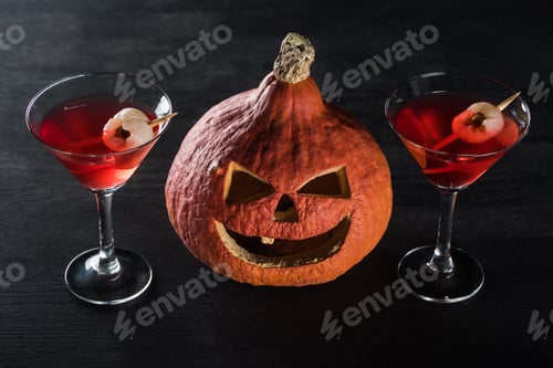 Preview: spooky Halloween pumpkin and red cocktails on black background
