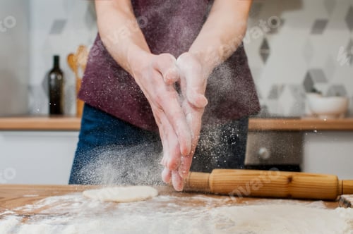 Preview: woman in the kitchen claps her hands with flour. Splashes of flour close-up