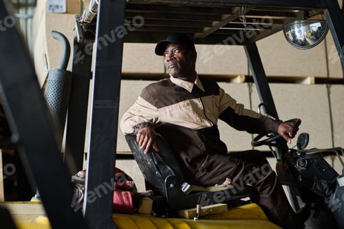 Preview: Male worker driving forklift in distribution warehouse