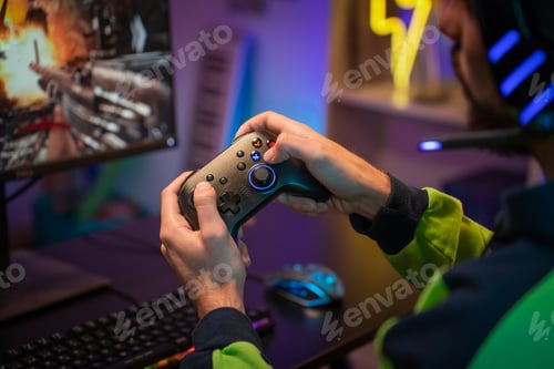 Preview: Gamer hands playing with joystick on green screen in trendy and stylish room with neon light