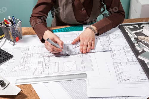 Preview: Architect woman at her table working on blueprints