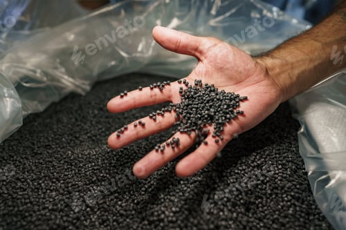 Preview: Close up of male hand holding plastic polymer granules