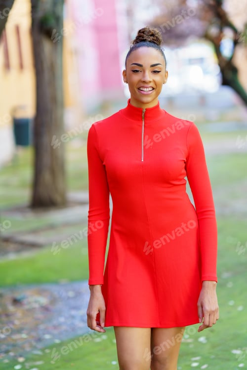 Preview: Smiling mixed woman in red dress walking down the street
