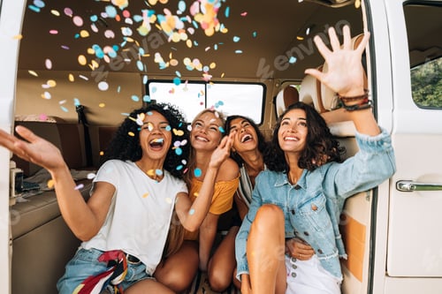 Preview: Women friends throwing confetti in the air while sitting in camper van