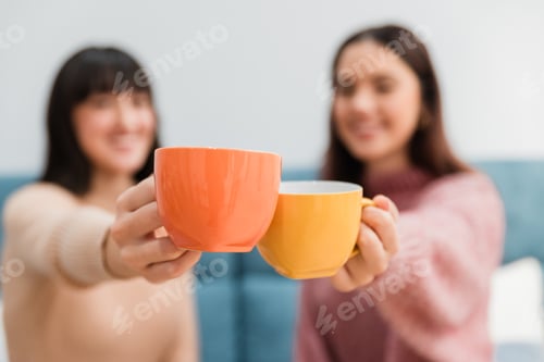 Preview: Female friends clinking cups with hot drinks