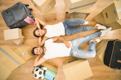 Preview: The happy man and woman lay on the floor near boxes. view from above