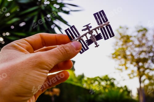 Preview: Space station figurine held with one hand against the sky, concept of space conquest.