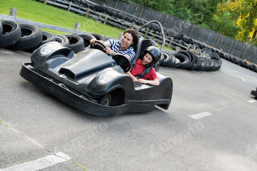Preview: Boys and men go-karting on a track.