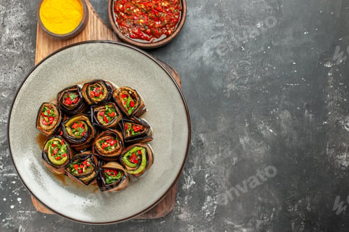 Preview: top view stuffed aubergine rolls in white oval plate turmeric in bowl on wooden serving board with