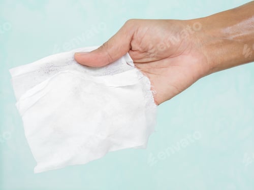 Preview: Hand woman holding wet wipe on green wall background