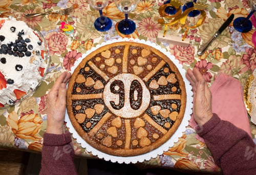 Preview: Senior woman holds her 90's birthday cake