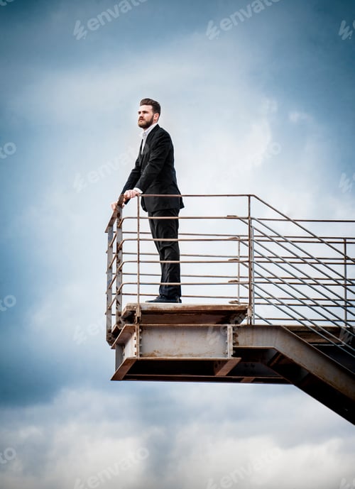 Preview: Low angle side view of mid adult man on stairs wearing suit looking away