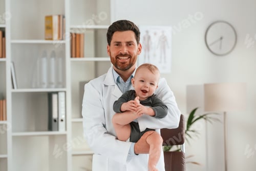 Preview: Standing and holding boy. Doctor with little baby is working in the cabinet