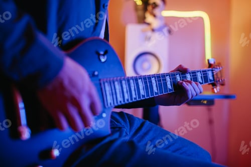 Preview: Musician playing electric guitar and writing music at home studio
