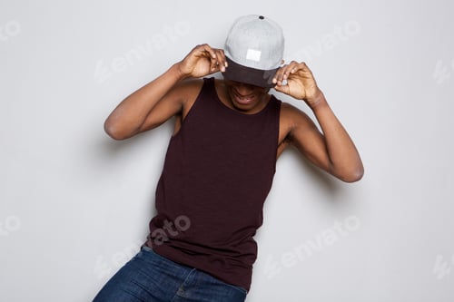 Preview: happy african american guy holding cap and looking down