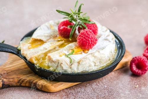 Preview: baked camembert cheese with rosemary leaves and raspberry. Homemade grilled brie on rustic table.