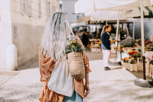 Preview: Beautiful young woman buying fresh flowers at city center market. Flower and food local market.
