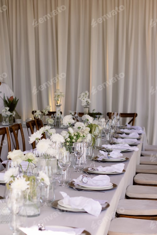Preview: Elegant floral arrangements with white flowers in vases on a table in a wedding venue