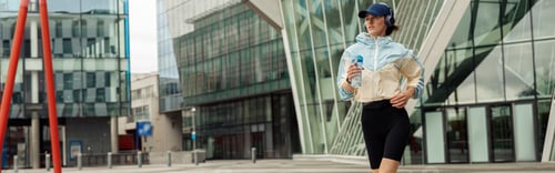 Preview: Young sportive woman in sportswear jogging in morning city background