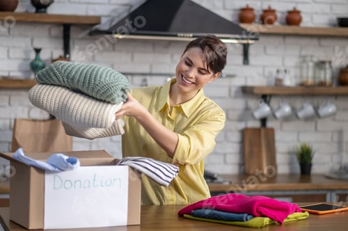 Preview: Joyous Caucasian girl preparing clothes for donation