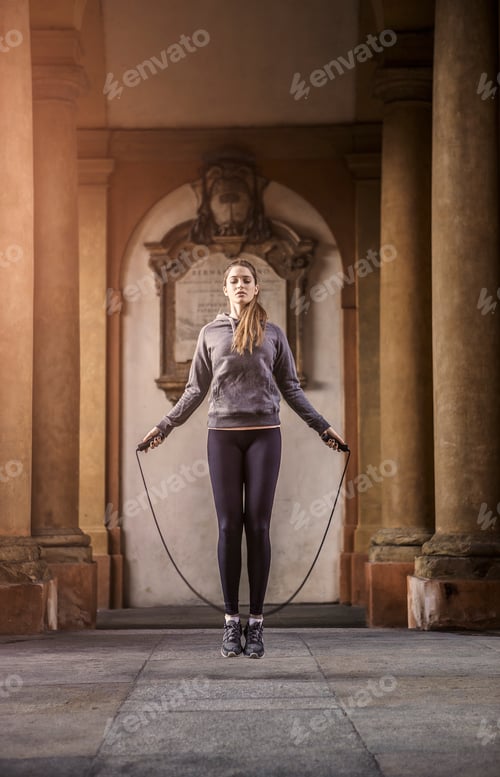 Preview: Front view of woman wearing sports clothes using skipping rope
