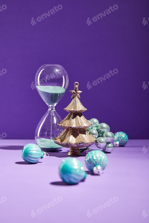 Preview: selective focus of decorative Christmas near blue baubles and hourglass on purple background