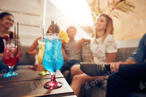 Preview: Cocktails on table with young people partying on rooftop