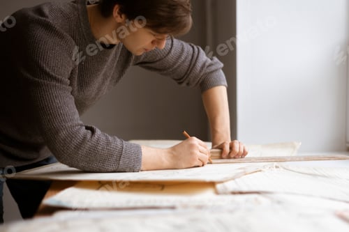 Preview: a caucasian young architect doing drawings at the workplace, making the sketch or draft of building