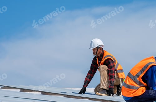 Preview: Roofer worker in protective uniform wear installing metal roof on top of the new roof.